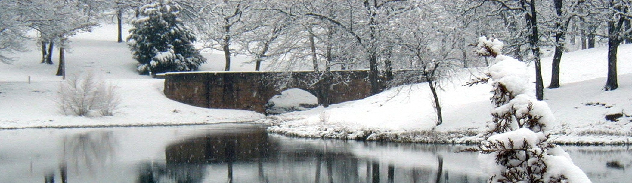 Bridge over a lake with surrounding area covered in snow.